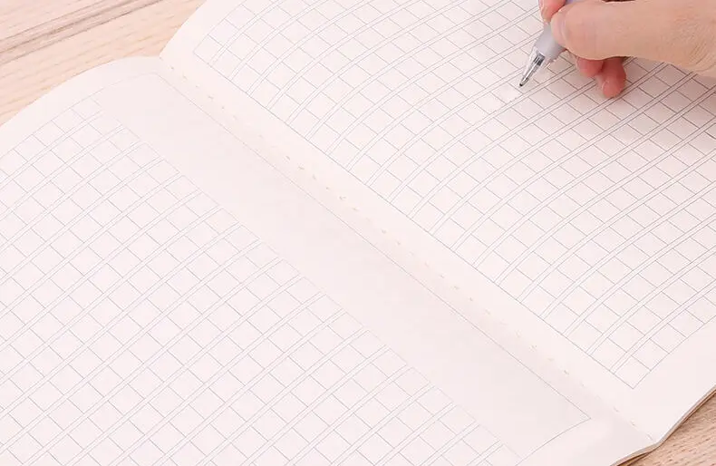 Open thread-sewn grid notebook with visible stitching along the center fold.
